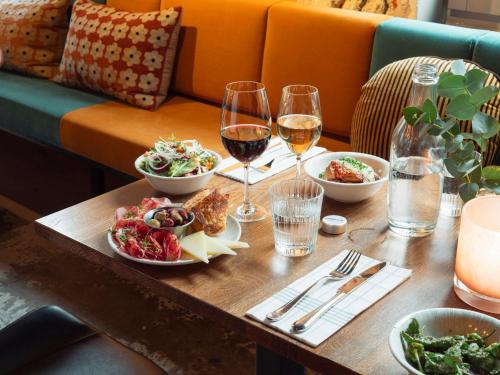 una mesa con platos de comida y copas de vino en Story Hotel Signalfabriken, part of JdV by Hyatt en Sundbyberg