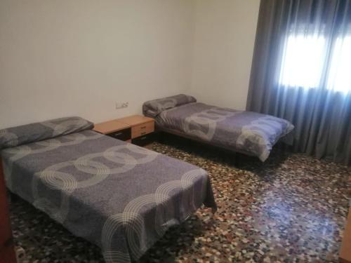 um quarto com 2 camas e uma janela com cortinas em Señora Isabel em Roquetas de Mar
