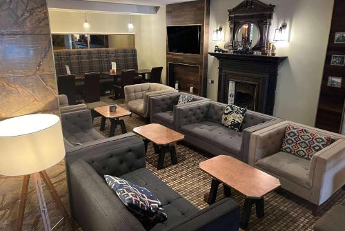 a living room with couches and tables and a fireplace at Heritage Park Pontypridd, Trademark Collection by Wyndham in Pontypridd