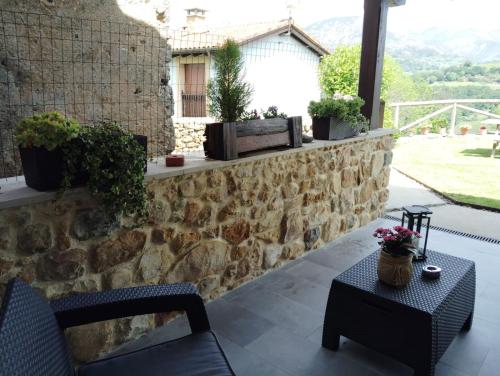 a patio with a stone wall and a table and chairs at Casa Rural Los Abuelos in Piloña