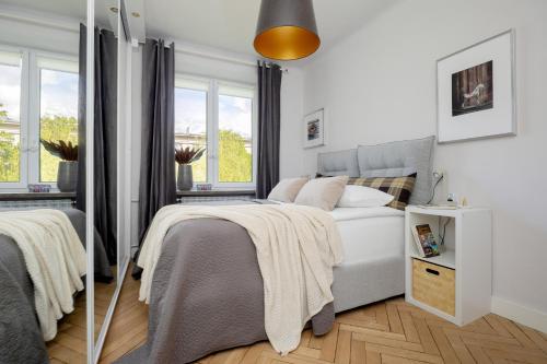 ein weißes Schlafzimmer mit einem Bett und zwei Fenstern in der Unterkunft Beautiful & Modern Apartment near the City Center by Renters in Warschau