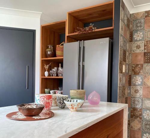 a kitchen with a refrigerator and some bowls on a counter at Relaxing Burleigh Heads Home with Swimming Pool in Gold Coast