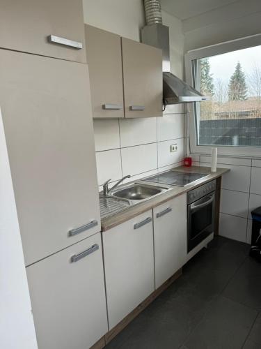uma cozinha com armários brancos, um lavatório e uma janela em Pension - Panorama em Gundelsheim