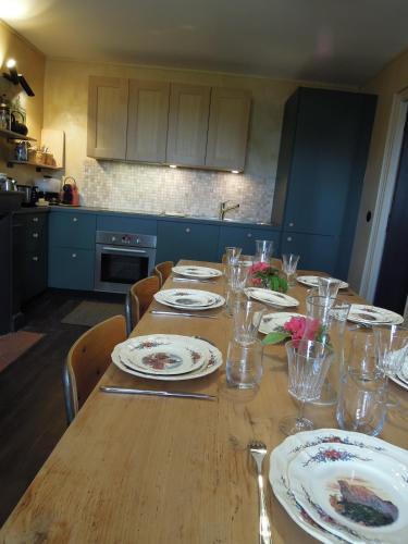 - une table en bois avec des assiettes et des verres dans la cuisine dans l'établissement Location Gîte 7-9 personnes proche de Giverny, à Chambray