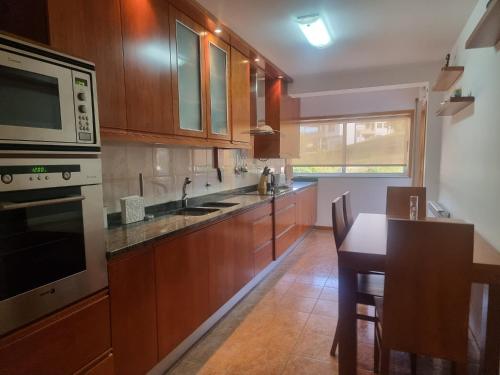 a kitchen with wooden cabinets and a table and a microwave at Minho House in Vieira do Minho