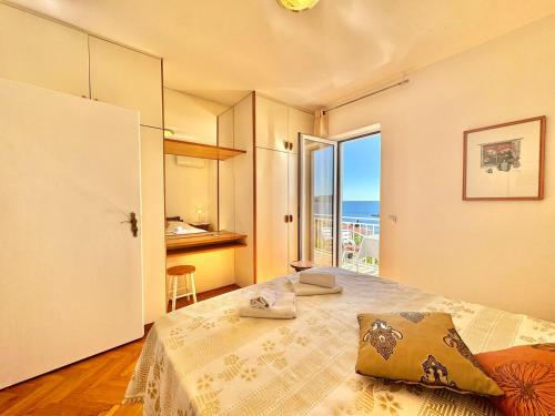 a bedroom with a bed with a view of the ocean at Sun Rose Apartments Sveti Stefan in Sveti Stefan