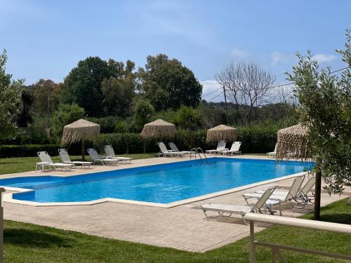 una piscina con tumbonas y sillas junto a un complejo en Mythos apts rentit en Agios Stefanos
