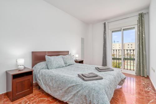a white bedroom with a bed and a large window at Casa Axarquia 2 in Vélez-Málaga
