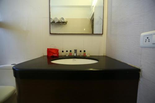 チェンナイにあるOYO NIMALAN RESIDENCYのバスルーム(黒い洗面台、鏡付)