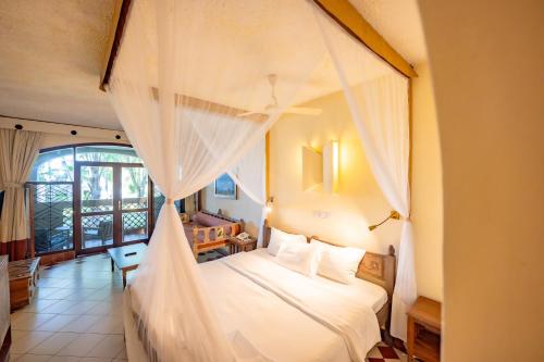 1 dormitorio con 1 cama blanca con dosel en Severin Sea Lodge, en Mombasa