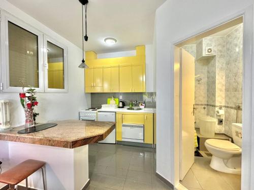 a kitchen with yellow cabinets and a toilet at Sun Rose Apartments Sveti Stefan in Sveti Stefan