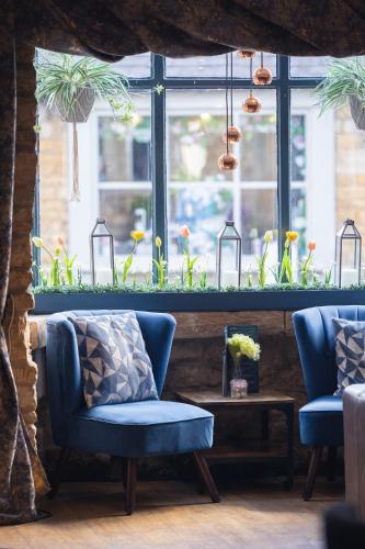 a room with two chairs and a window with plants at Chester House Hotel in Bourton on the Water