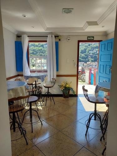 Habitación con mesas, sillas y ventana en Pousada Ouro Preto, en Ouro Preto