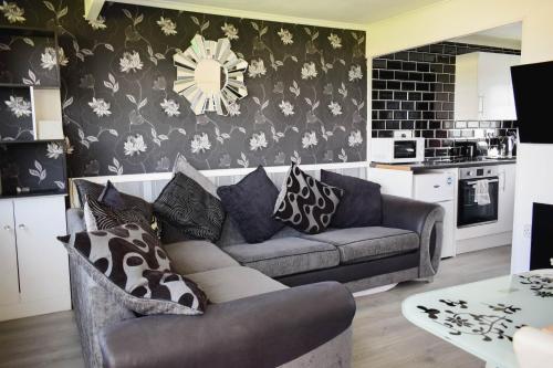 a living room with a couch and a clock on the wall at Family Chalets - 5 mins walk to beach, nr Great Yarmouth & Norfolk Broads in Scratby
