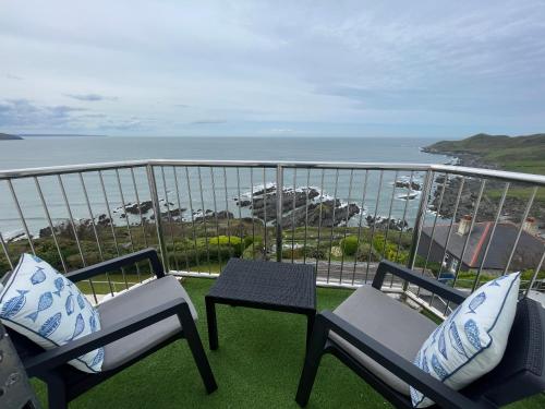 a balcony with two chairs and a table and the ocean at Lundy House Hotel in Woolacombe