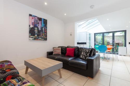 a living room with a black leather couch and a table at Trendy Terraced House in Central Oxford in Oxford