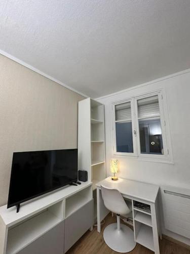 une pièce blanche avec un bureau et une télévision à écran plat dans l'établissement Parisian Stay in a Cosy Flat - République, à Paris