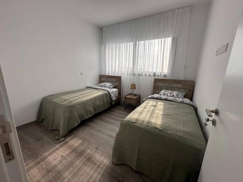 2 camas en una habitación pequeña con ventana en Cozy 3 Bedroom Apartment 300M from the SEA en Lárnaca
