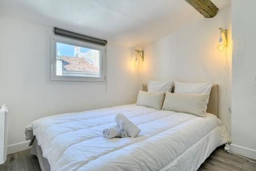 um quarto com uma grande cama branca e uma janela em nid douillet près du vieux port em Marselha