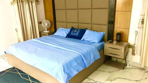 sypialnia z łóżkiem z niebieską pościelą i szafką nocną w obiekcie 001 Apartments w mieście Oshogbo