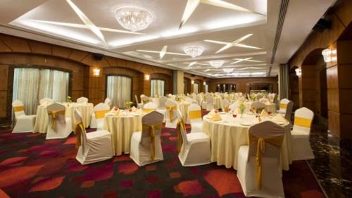 un salón de banquetes con mesas blancas y sillas blancas en Lee Grande en Gūduvāncheri
