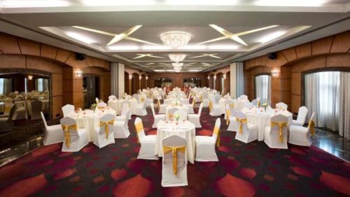 un salón de banquetes con mesas y sillas blancas en Lee Grande en Gūduvāncheri