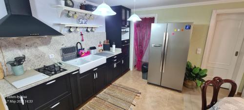 a large kitchen with a refrigerator and a sink at Casa do Amigo in Seixal