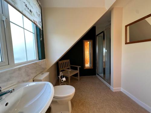 a bathroom with a sink and a toilet and a staircase at The Cow Shed in Narberth