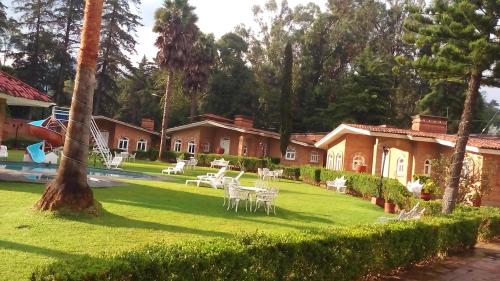 a house with a yard with chairs and a pool at Hotel Villa Monarca Inn in Zitácuaro