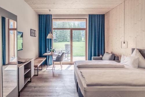 a hotel room with two beds and a desk and a window at Boutique Hotel LechZeit in Elmen