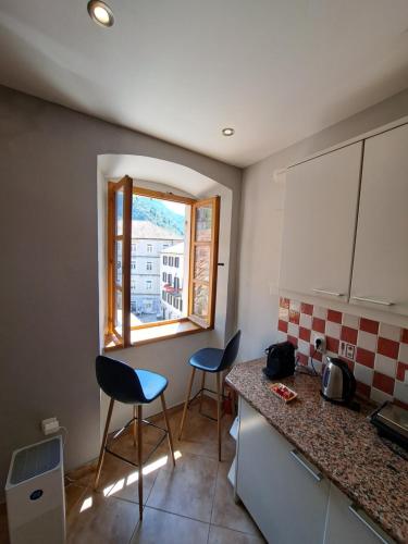 a kitchen with two chairs and a counter and a window at Cozy 2 Bedroom Apartment in Antique Bizanti Palace in Kotor