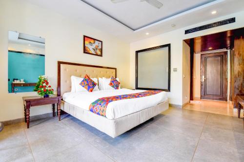 a bedroom with a large bed and a table at FabHotel Prime The King's Court Calangute with Pool and Bar in Calangute