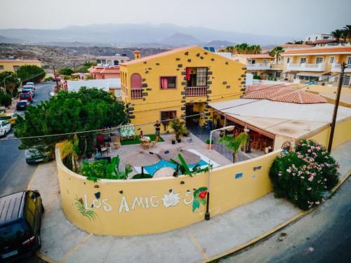 vista aerea di un edificio giallo con piscina di Hostel Los Amigos by Youroom a La Mareta