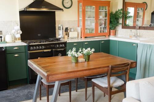 a kitchen with green cabinets and a wooden table with flowers at Southsea, Portsmouth - Two Bedroom Apartment - Newly Refurbished Throughout - Treetop Sea Views in Portsmouth