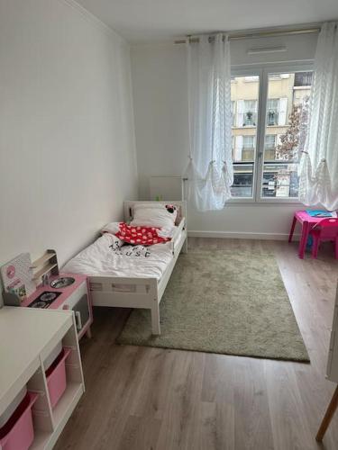 une petite pièce avec un lit et une fenêtre dans l'établissement Appartement Saint Ouen Sur Seine, à Saint-Ouen