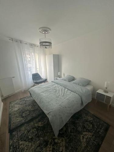 une chambre blanche avec un lit et une chaise dans l'établissement Appartement Saint Ouen Sur Seine, à Saint-Ouen