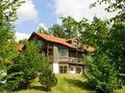 une grande maison avec des arbres devant elle dans l'établissement Apartment Bayrischer Wald am Golfclub im Feriendorf Glasgarten, à Rötz