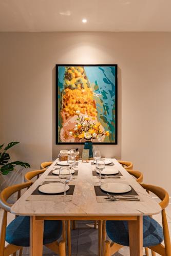 a table with chairs and a painting on the wall at Luxury 2 or 3BR Apartment in Dist 1, Pool and airport pickup in Ho Chi Minh City