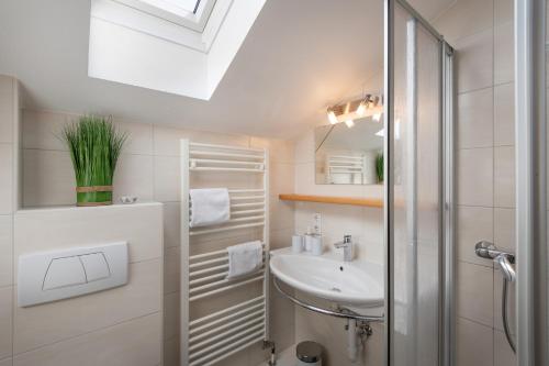 ein weißes Bad mit einem Waschbecken und einer Dusche in der Unterkunft Hofer's Wiesenheim in Zell am Ziller