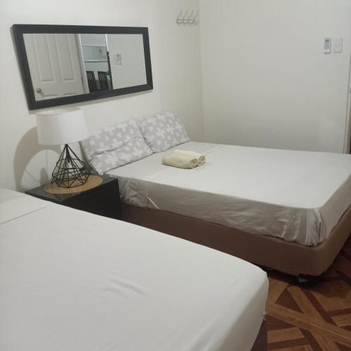 two beds in a room with a mirror and a couch at Affordable Makati APT in Manila