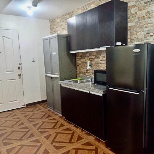 a kitchen with a black refrigerator and a sink at Affordable Makati APT in Manila