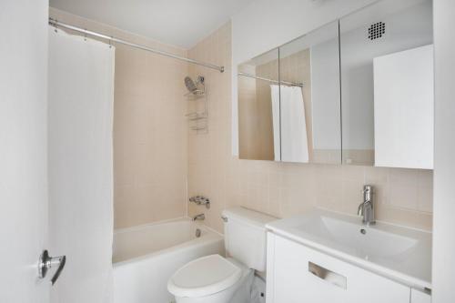 La salle de bains blanche est pourvue de toilettes et d'un lavabo. dans l'établissement Chelsea 1br w doorman rooftop nr shops food NYC-1193, à New York