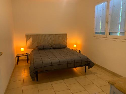 - une chambre avec un lit et deux lampes sur deux tables dans l'établissement Petite maison dans un village du Gers, à Sabazan