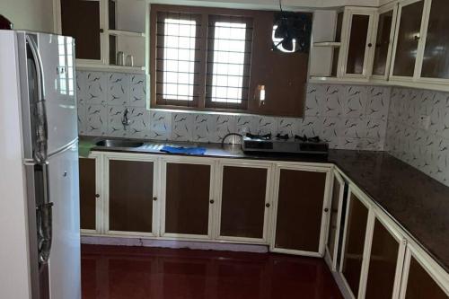 a kitchen with wooden cabinets and a white refrigerator at Independent 3 Bedroom House Kottayam in Kottayam