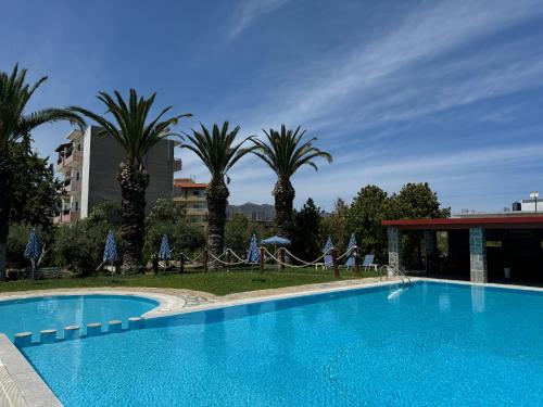 a large swimming pool with palm trees and a building at Zac & Georgio Studios in Amoudara Herakliou