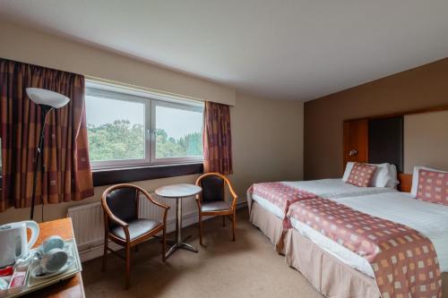 a hotel room with two beds and a table and chairs at Normandy Hotel (Near Glasgow Airport) in Paisley
