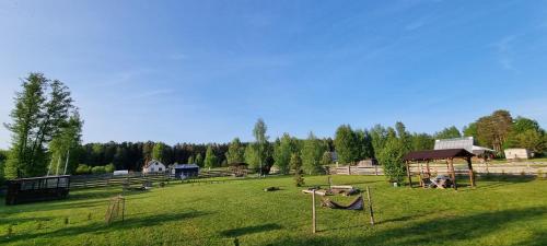 un terrain avec un parc agrémenté d'une aire de jeux et d'arbres dans l'établissement Kempings Roja - TELTS vietas, à Roja