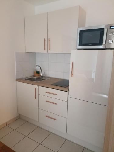 une cuisine blanche avec un évier et un micro-ondes dans l'établissement Studio tout confort Massy-Paris, à Massy