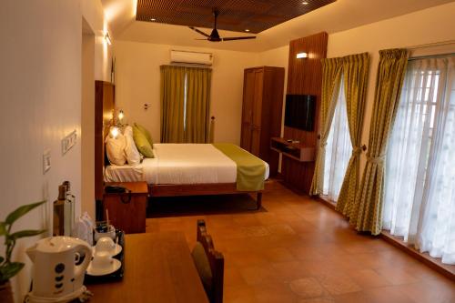 a bedroom with a bed and a television in it at KTDC Kumarakom Gateway Resort in Alleppey