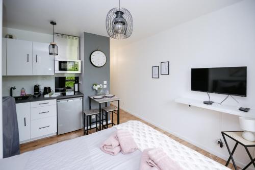 a room with a bed and a kitchen with a tv at NeuvaRoom in Montévrain